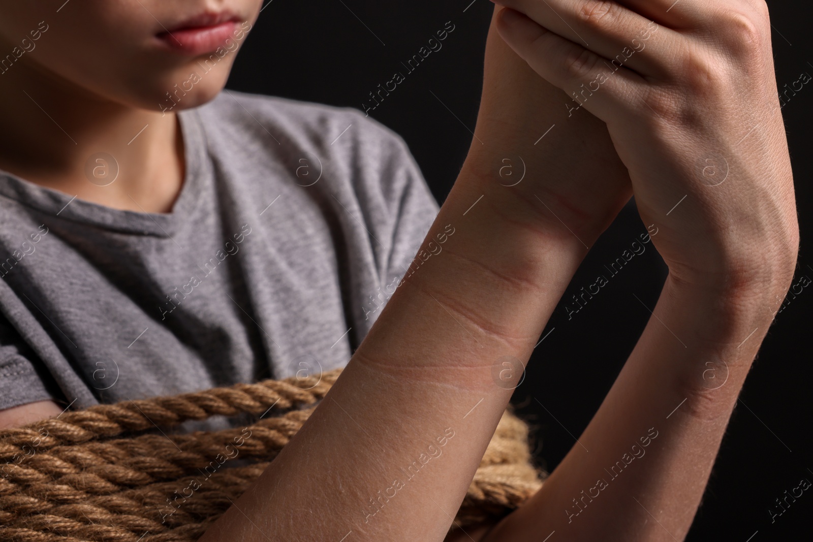 Photo of Little boy tied up and taken hostage on dark background, closeup