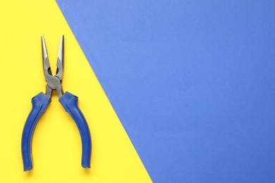 Needle nose pliers on color background, top view. Space for text