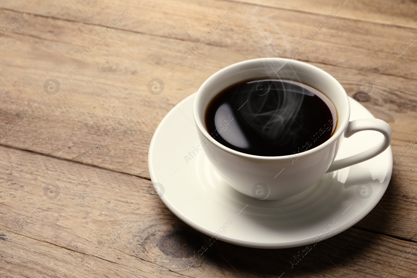 Image of Steaming coffee in cup on wooden table. Space for text