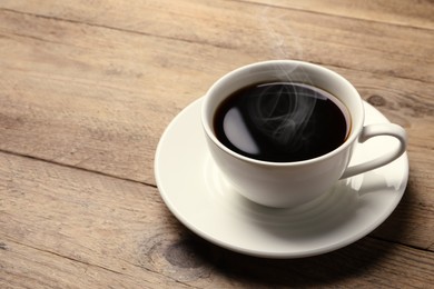 Image of Steaming coffee in cup on wooden table. Space for text