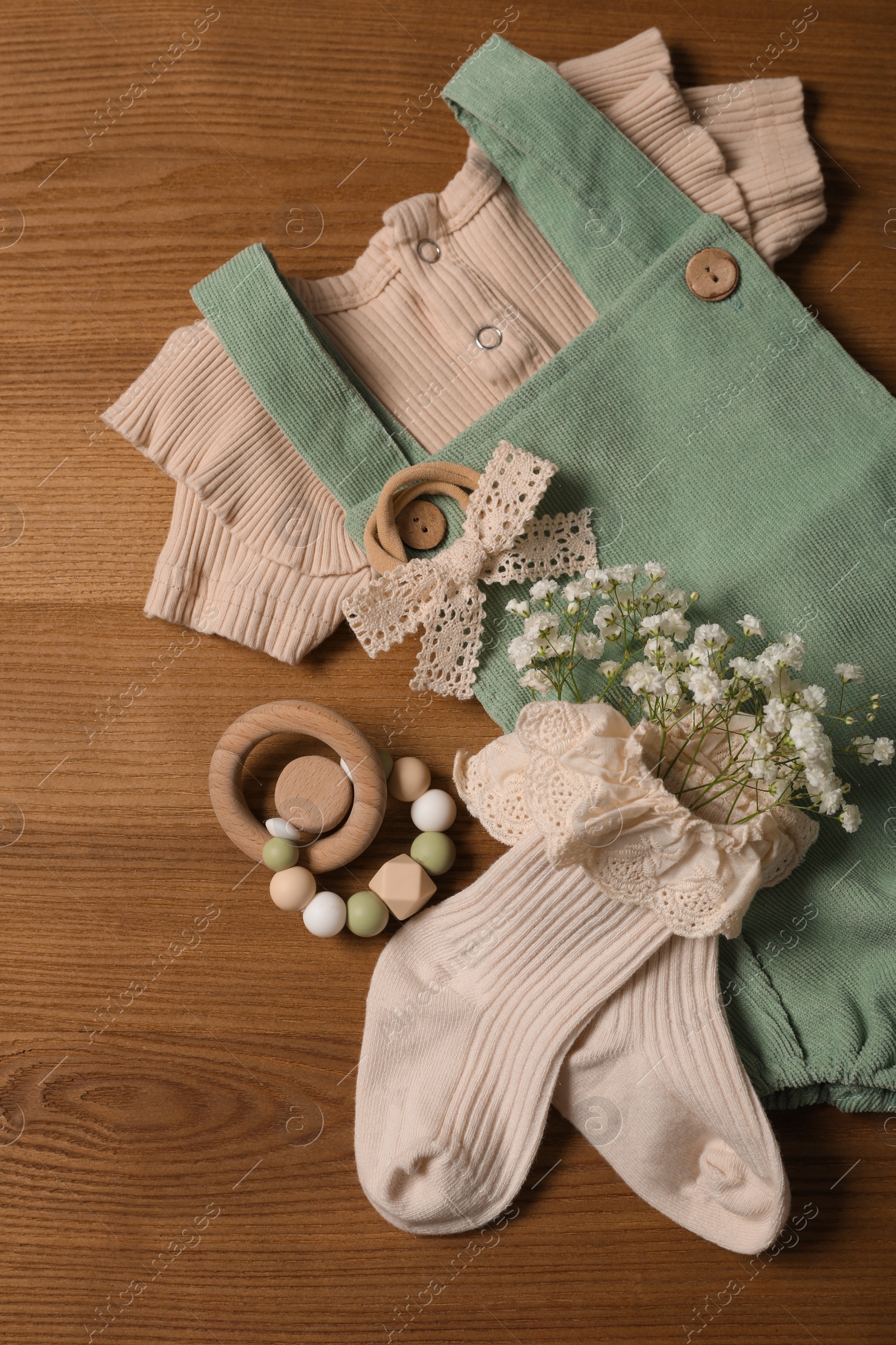 Photo of Children's clothes and toy on wooden table, flat lay