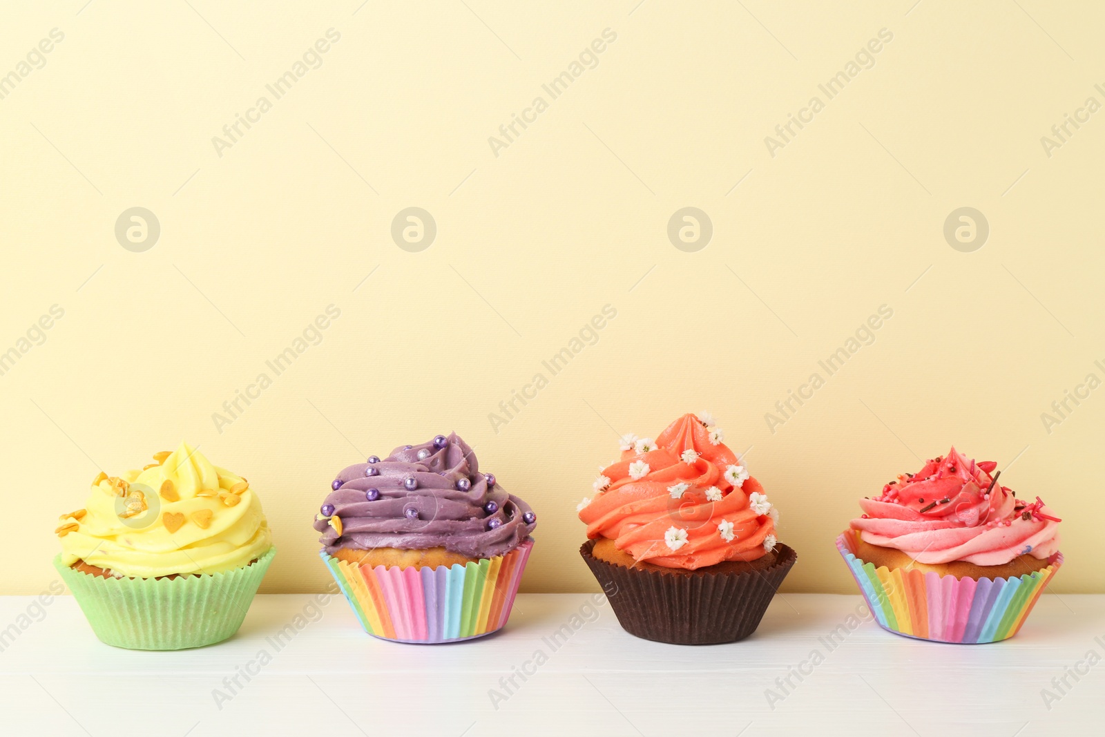 Photo of Delicious cupcake with bright cream on white wooden table. Space for text