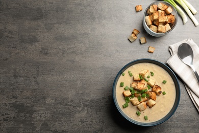 Flat lay composition with bowl of fresh homemade mushroom soup and space for text on gray background