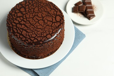Photo of Delicious truffle cake and chocolate pieces on white table