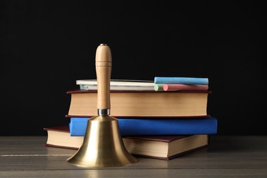 Golden bell, books and pieces of chalk on wooden table near blackboard. School days