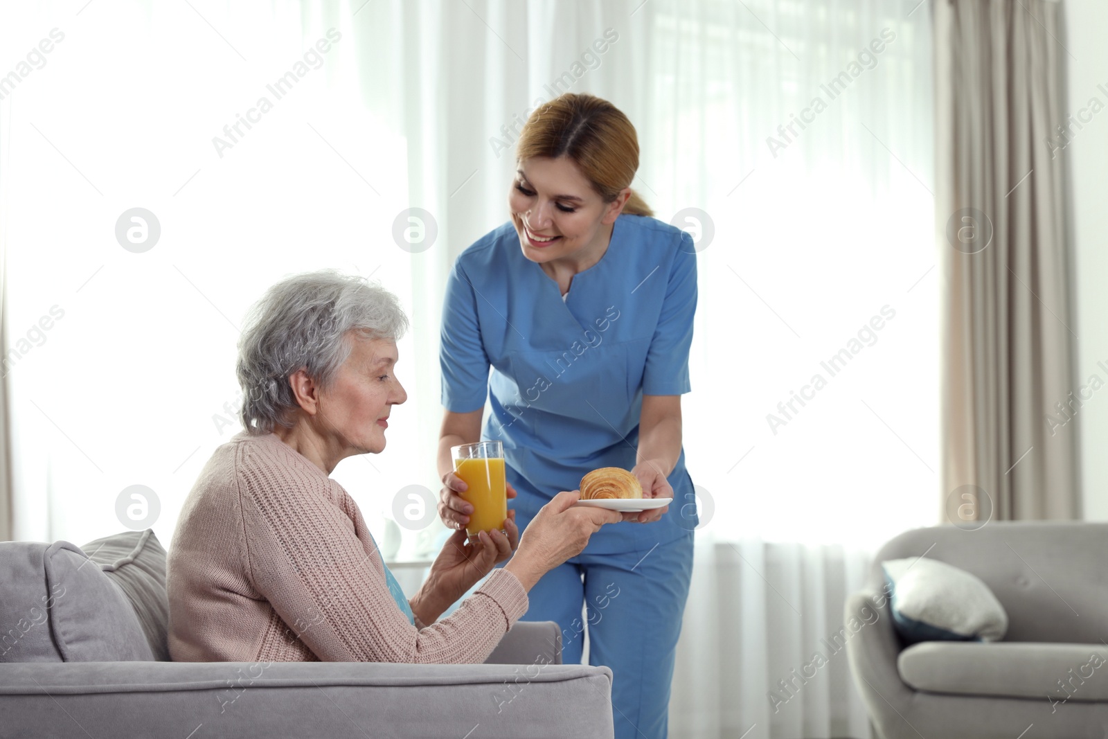 Photo of Nurse serving breakfast to elderly woman indoors, space for text. Assisting senior people