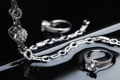 Photo of Luxury jewelry. Elegant ring and bracelet on black mirror surface
