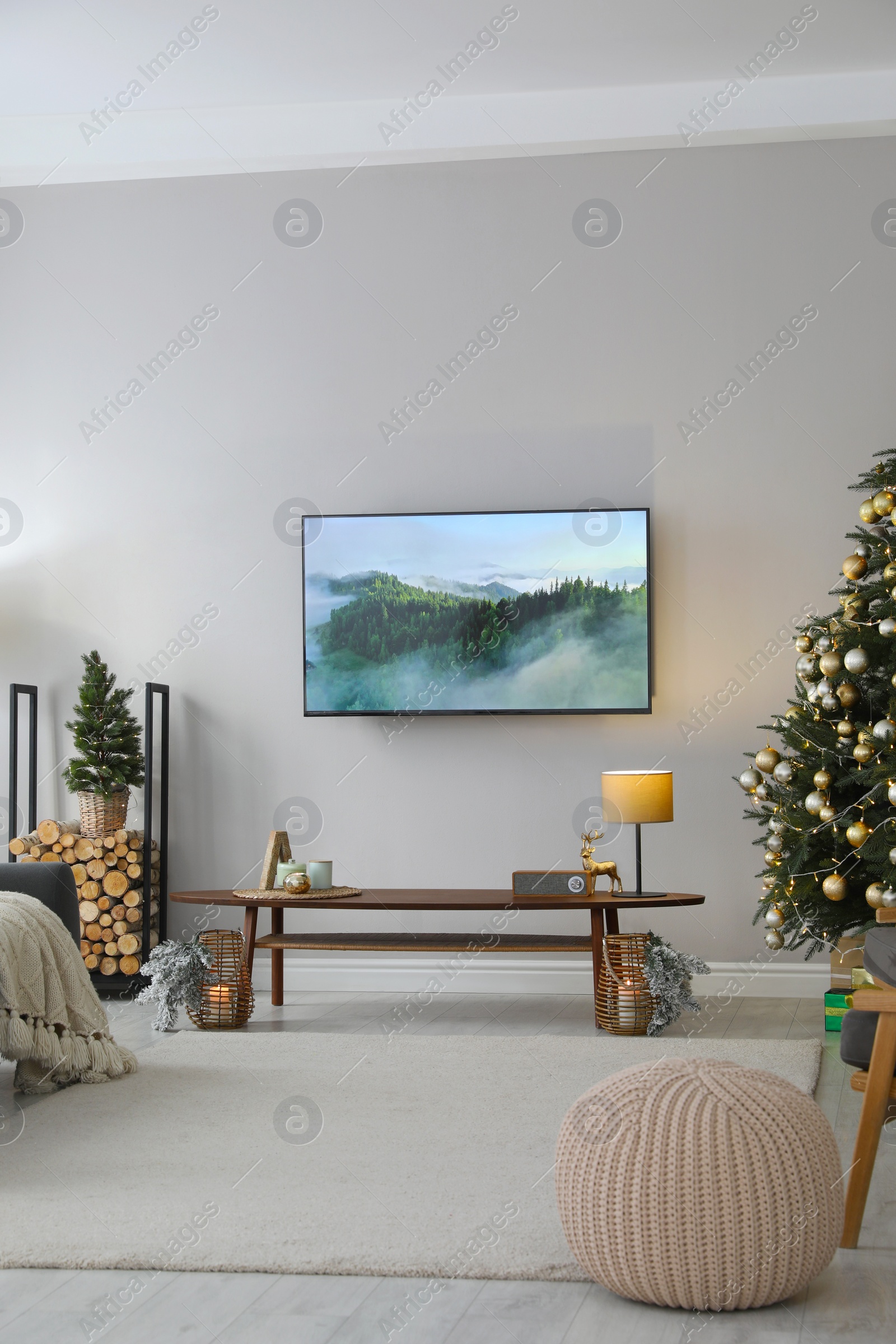 Photo of Modern TV set on light wall in room decorated for Christmas