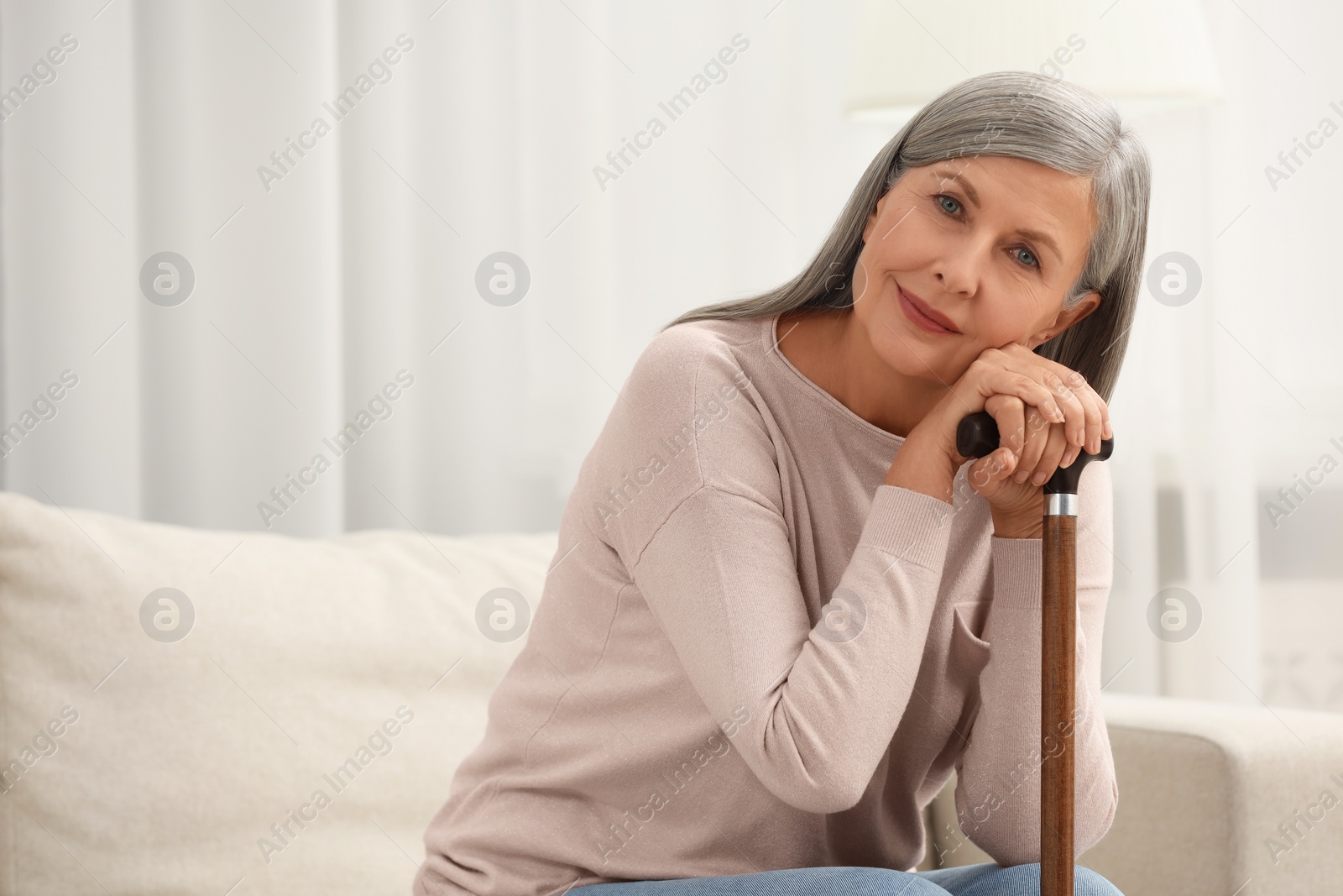 Photo of Mature woman with walking cane on sofa indoors