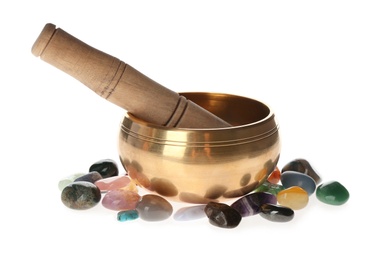 Golden singing bowl with mallet and healing stones on white background