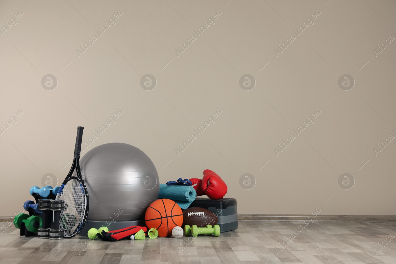 Photo of Set of different sports equipment on floor near beige wall, space for text