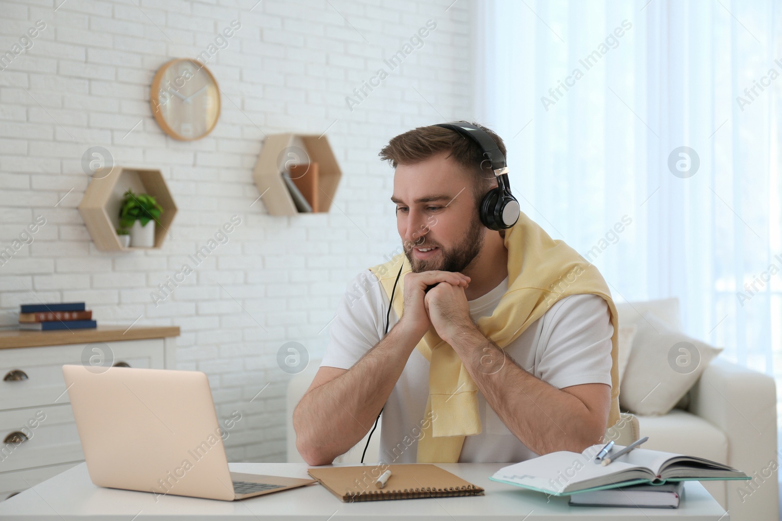 Photo of Young man watching online webinar at table indoors