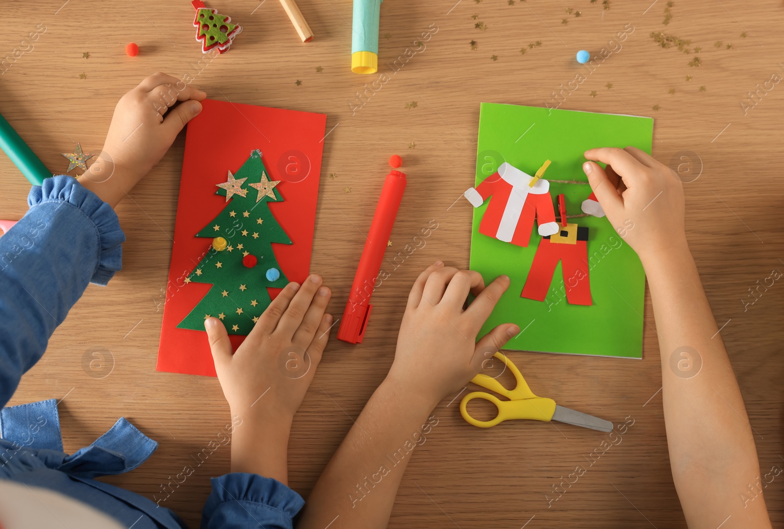 Photo of Little children making beautiful Christmas greeting cards at wooden table, top view