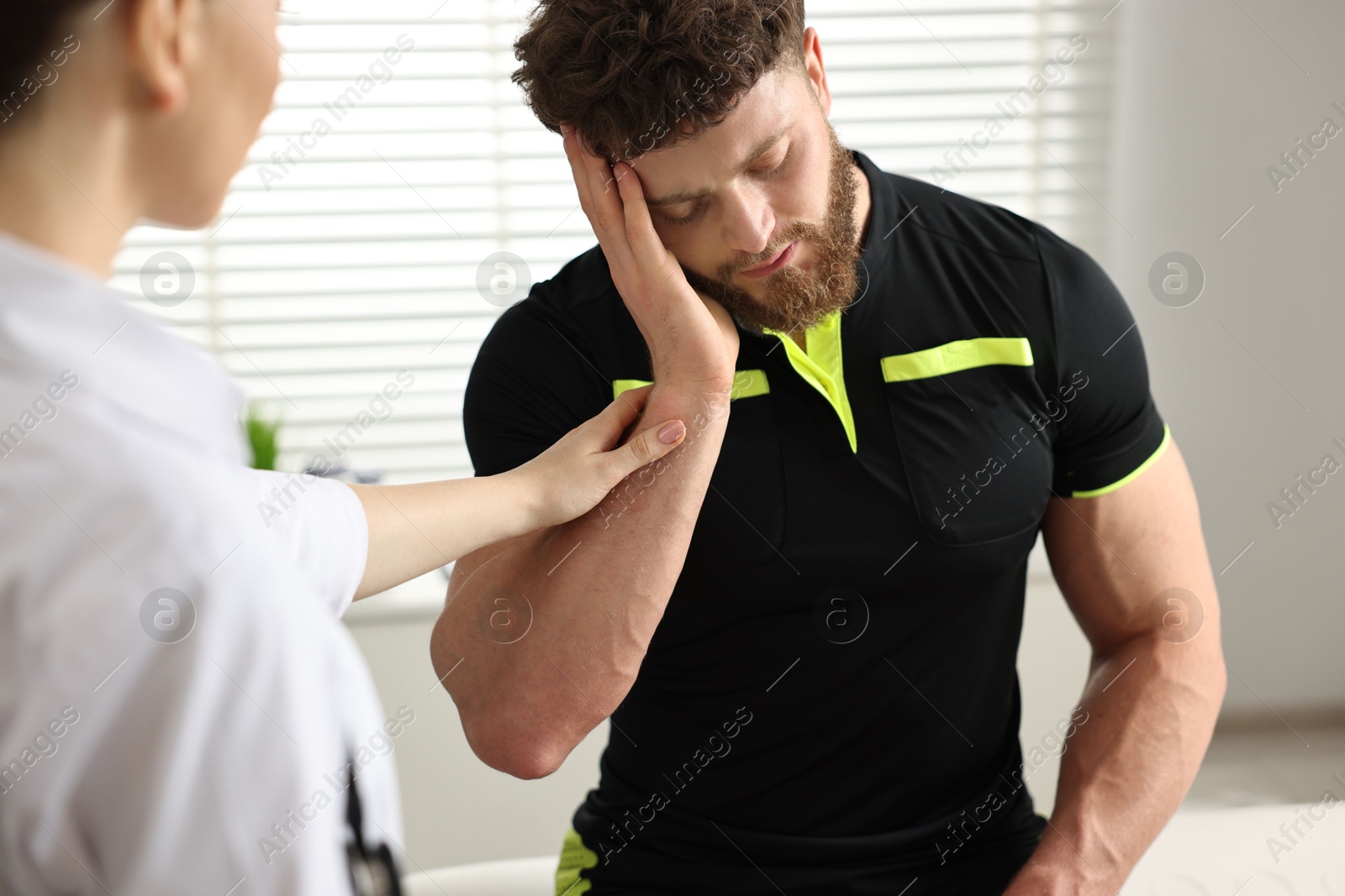 Photo of Doctor examining injured sportsman in hospital, closeup