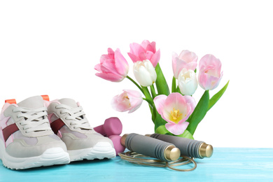 Photo of Composition with spring flowers and sports items on light blue wooden table against white background