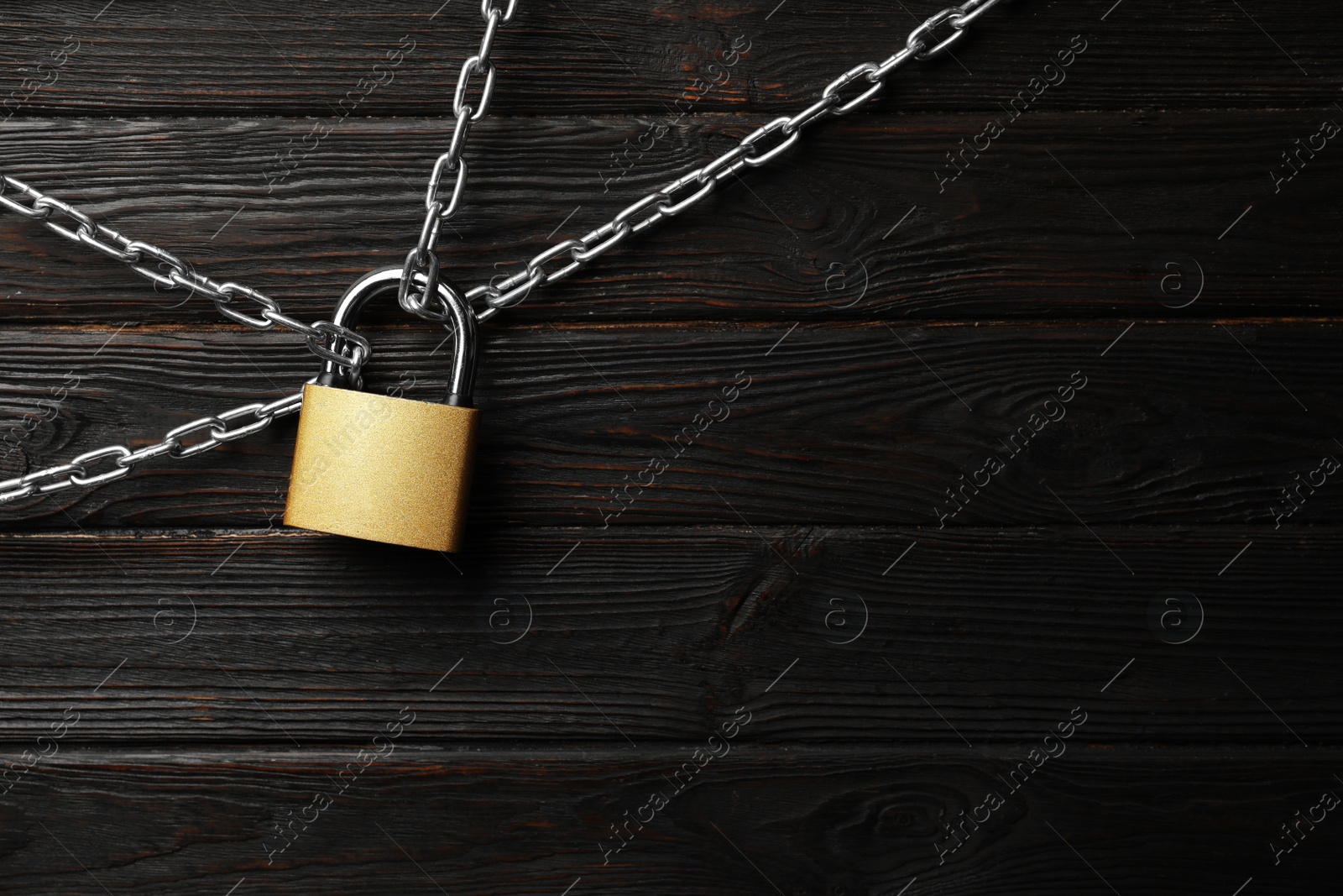 Photo of Steel padlock, chains and space for text on black wooden background, flat lay. Safety concept