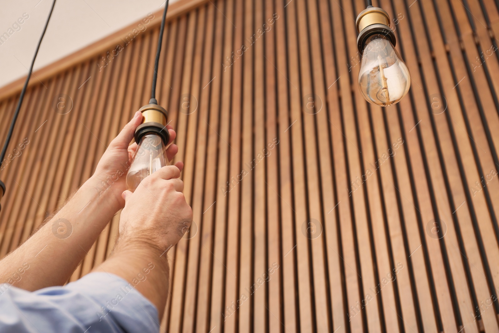 Photo of Man changing lamp light bulb indoors, closeup. Space for text