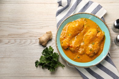 Photo of Tasty chicken curry, parsley and ginger on wooden table, flat lay. Space for text