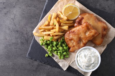 Photo of Tasty fish, chips, sauce and peas on grey table, top view. Space for text