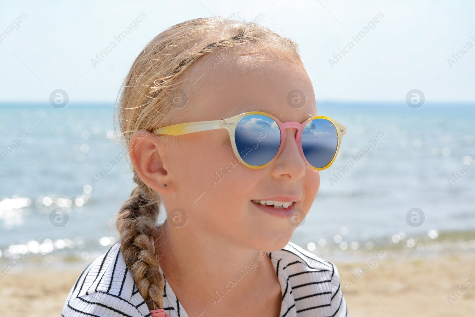 Photo of Little girl wearing sunglasses at beach on sunny day