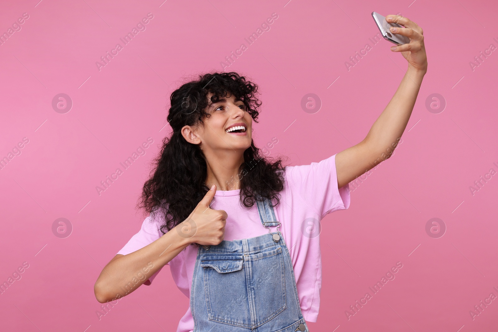 Photo of Beautiful young woman taking selfie on pink background