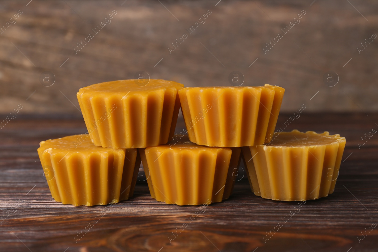 Photo of Natural beeswax cake blocks on wooden table, closeup