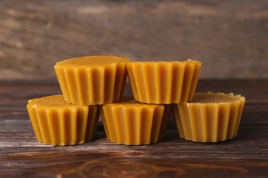 Photo of Natural beeswax cake blocks on wooden table, closeup
