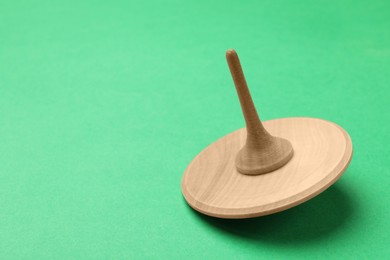 Photo of One wooden spinning top on aquamarine background, closeup. Space for text