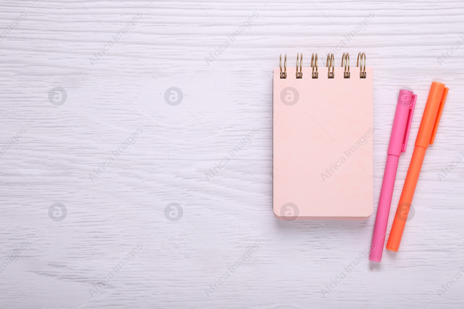 Photo of Notebook and colorful markers on white wooden background, flat lay. Space for text