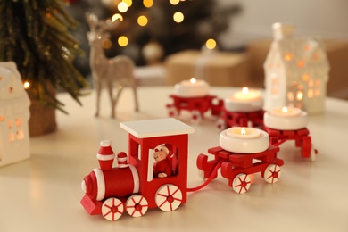 Photo of Red toy train as Christmas candle holder on white table in room