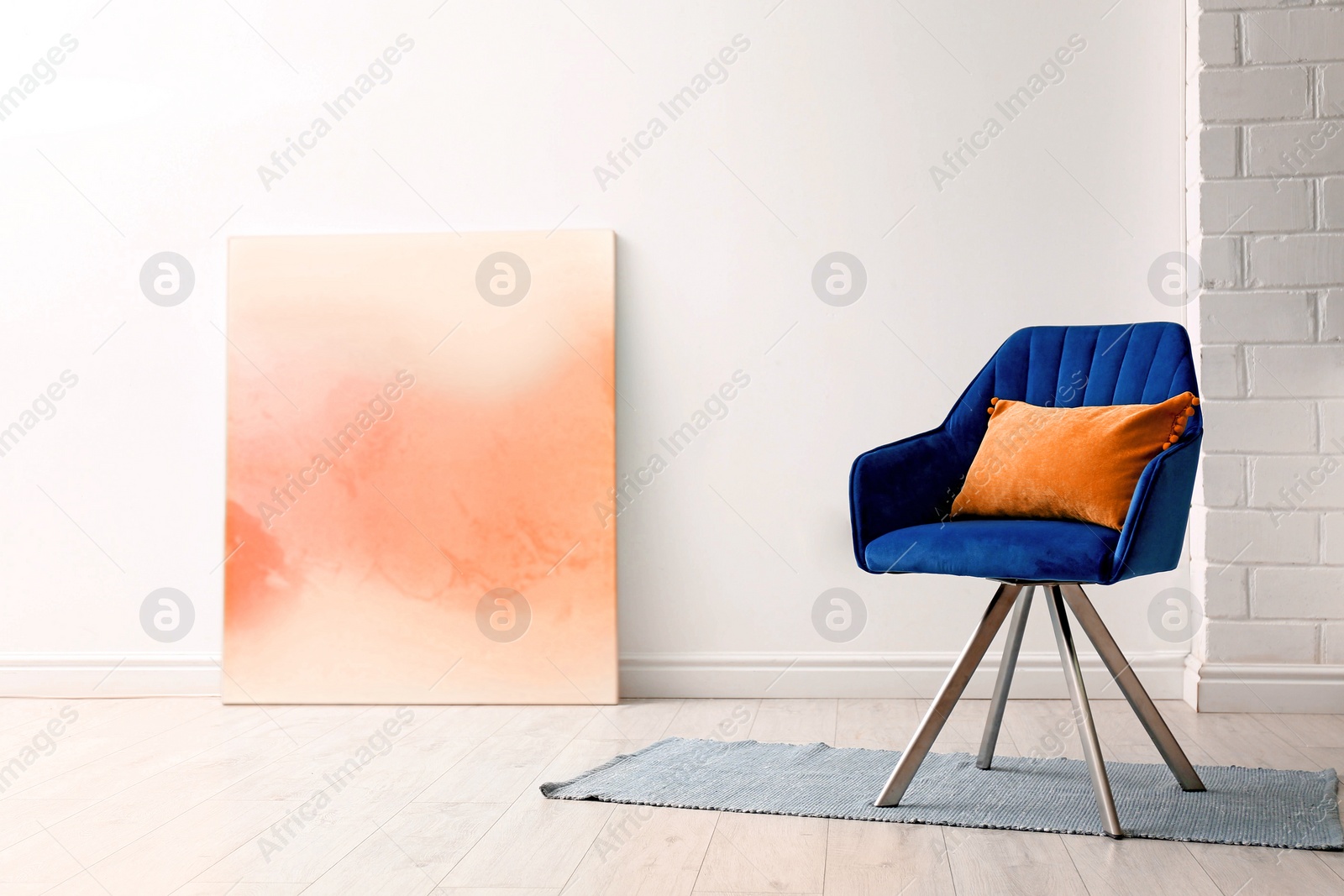 Image of Comfortable armchair with orange cushion in stylish room interior