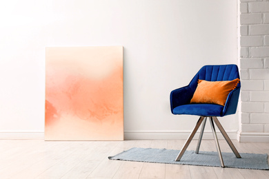 Image of Comfortable armchair with orange cushion in stylish room interior