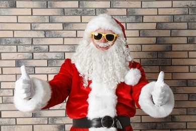 Authentic Santa Claus wearing sunglasses on brick wall background