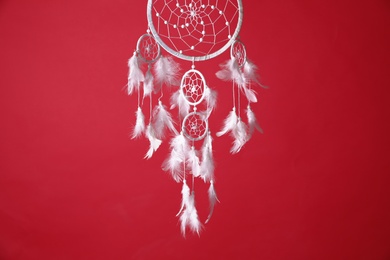 Photo of Beautiful dream catcher hanging on red background