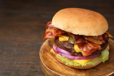 Photo of Tasty burger with bacon, vegetables and patty on wooden table, closeup. Space for text