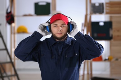 Worker wearing safety headphones indoors. Hearing protection device