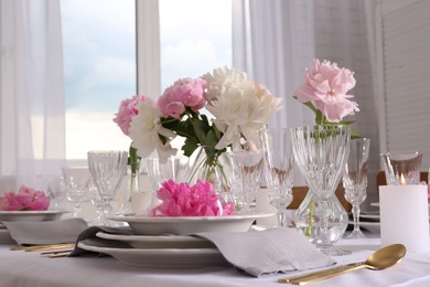 Stylish table setting with beautiful peonies in dining room, closeup