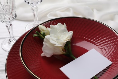 Photo of Stylish table setting. Dishes, glasses, blank card and flower on white background, closeup