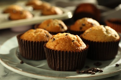 Photo of Delicious sweet muffins with chocolate chips on white marble table, closeup