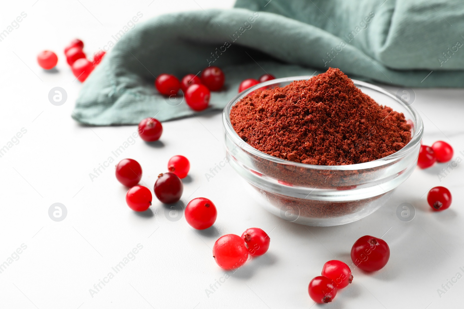 Photo of Dried cranberry powder in bowl and fresh berries on white table. Space for text