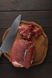 Pieces of raw beef meat and knife on wooden table, top view