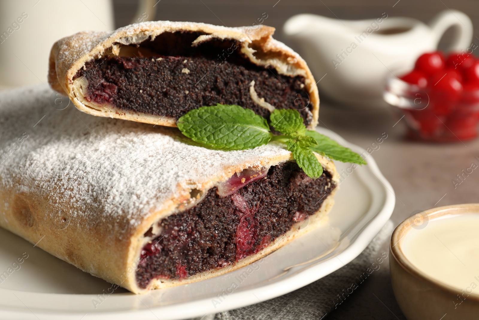 Photo of Delicious strudel with cherries and poppy seeds on grey table, closeup
