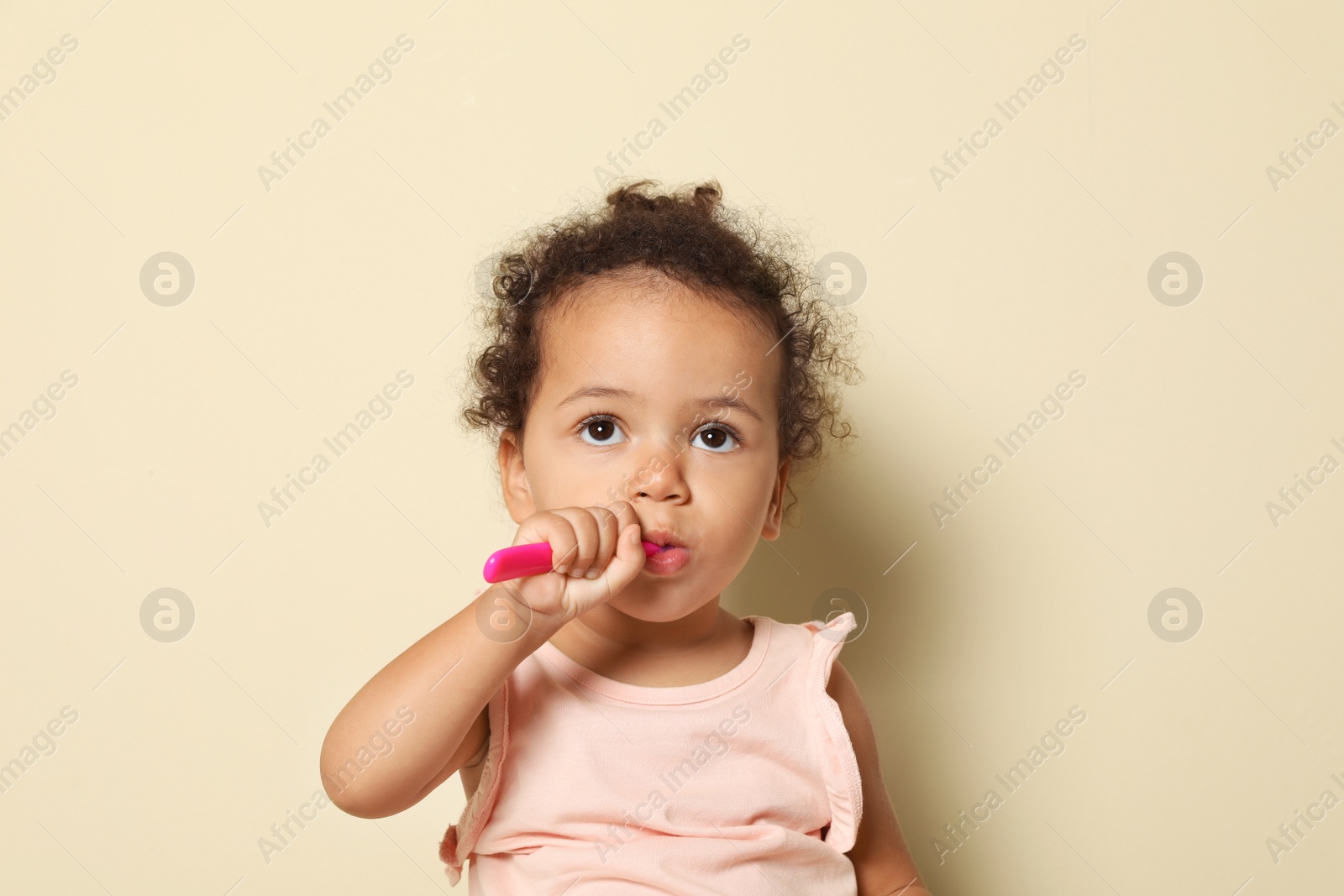 Photo of Cute African-American girl with toothbrush on color background