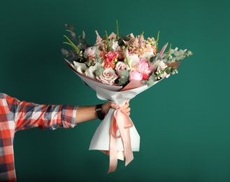 Photo of Man holding beautiful flower bouquet on green background, closeup view