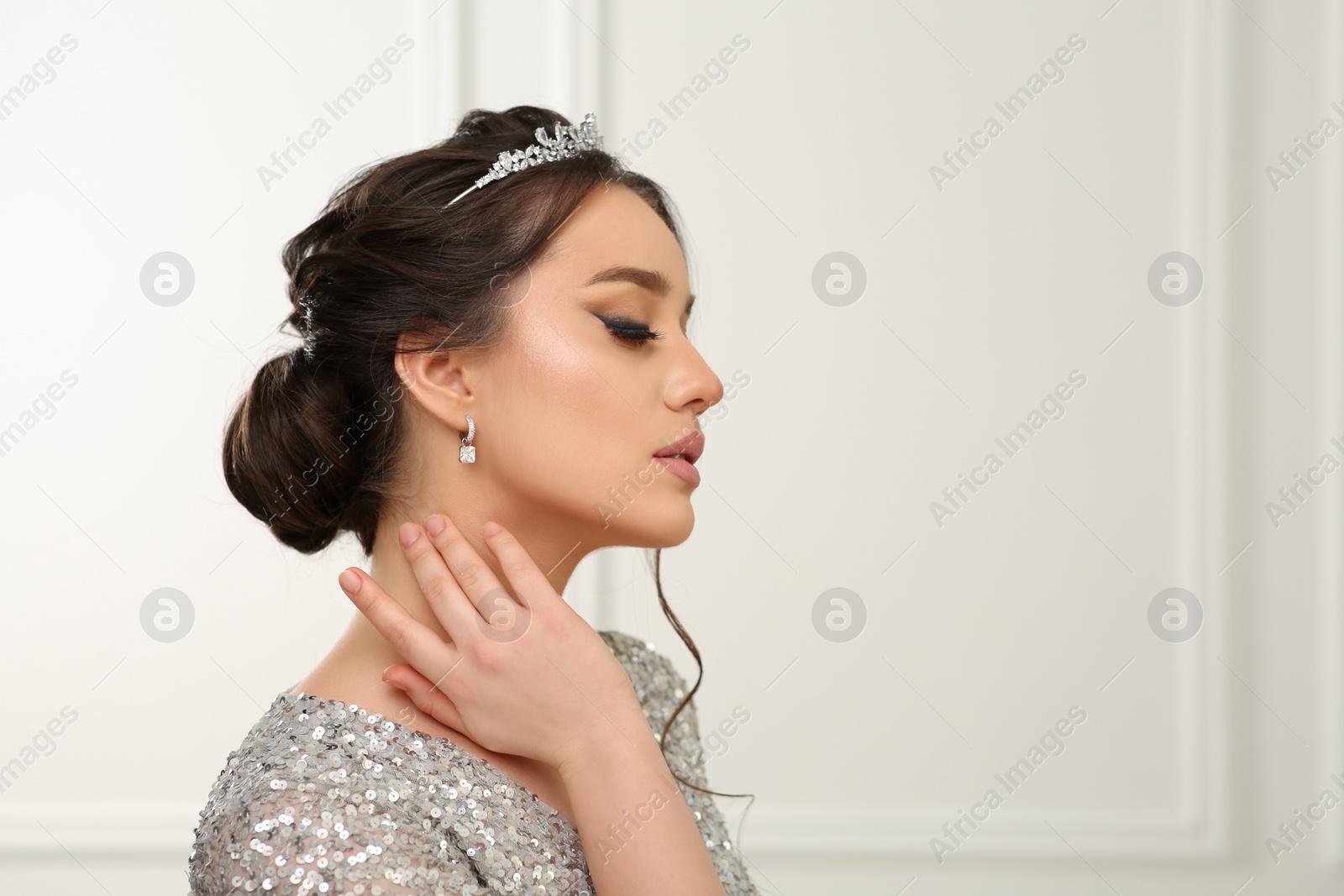 Photo of Beautiful young woman wearing luxurious tiara indoors, space for text