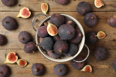 Photo of Whole and cut tasty fresh figs on wooden table, flat lay