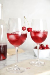 Delicious cherry wine with ripe juicy berries on white marble table