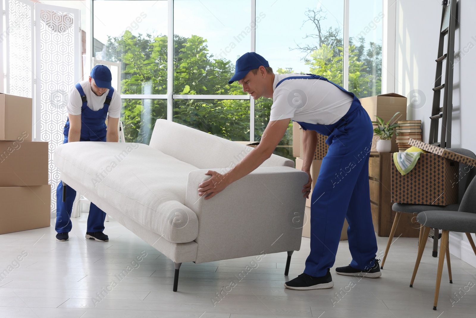 Photo of Moving service employees carrying sofa in room