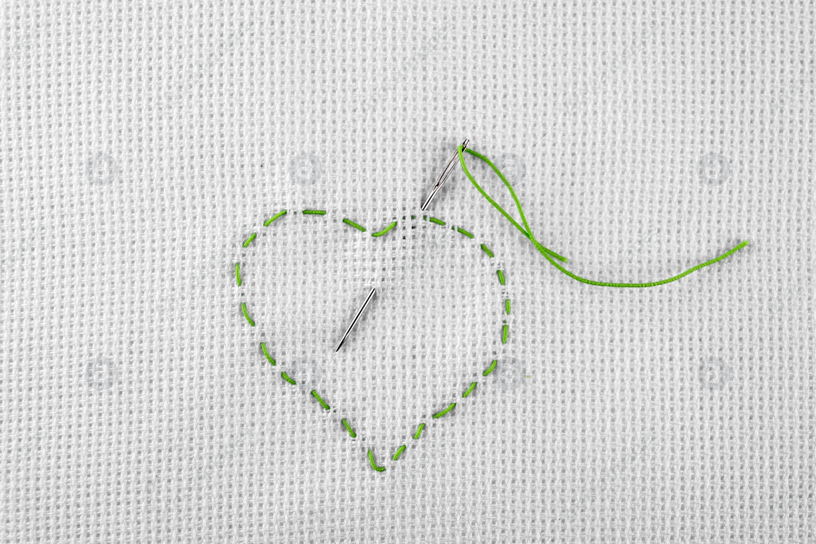 Photo of Canvas with embroidered heart and needle as background, top view