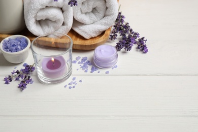 Photo of Cosmetic products and lavender flowers on white wooden table. Space for text